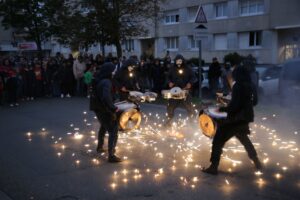 des batteurs avec des caisses à résonance forment un cercle autour d'un objet pyrotechnique entouré par les habitants