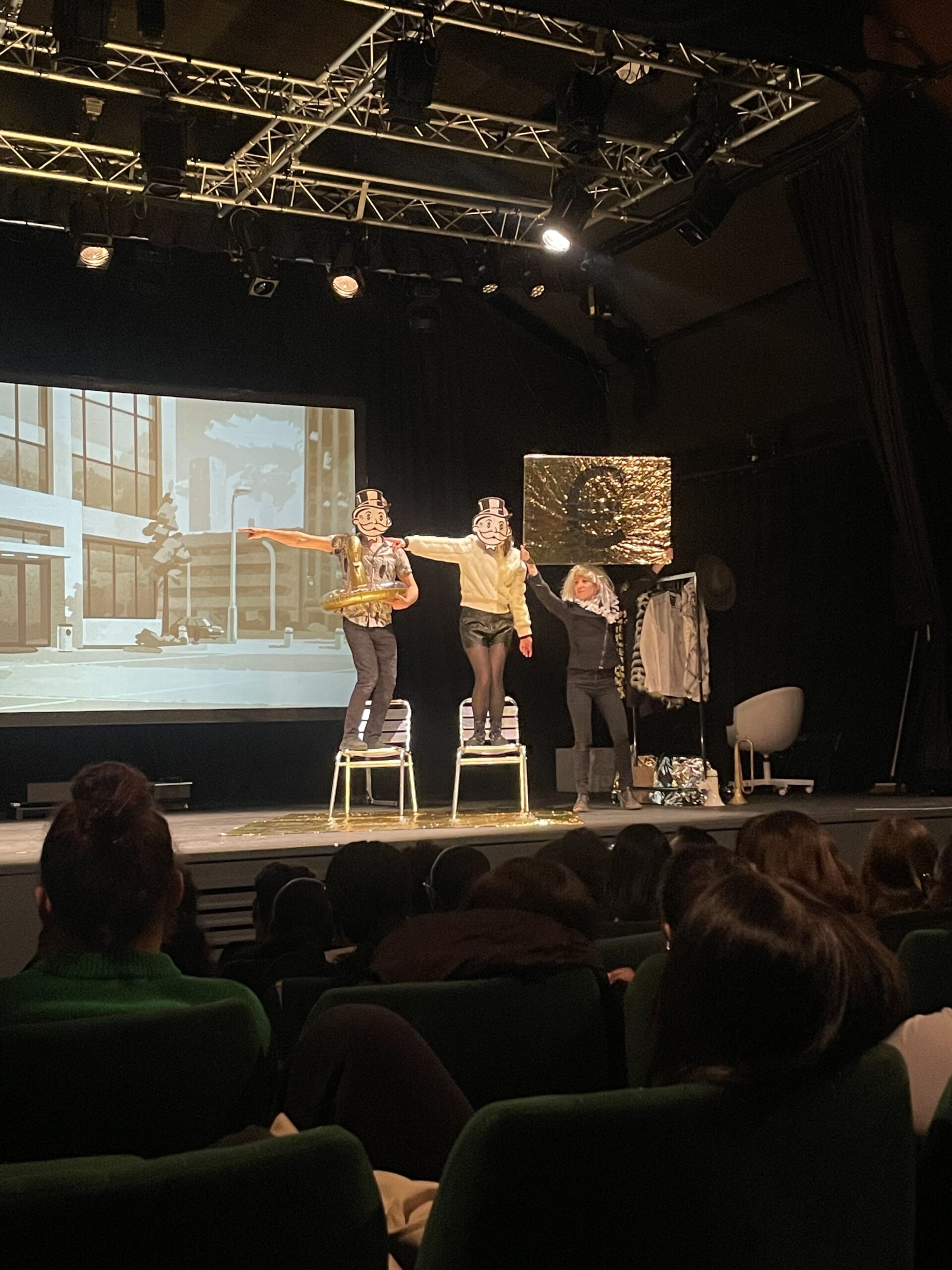 groupe de comédiens sur scène avec des pancartes